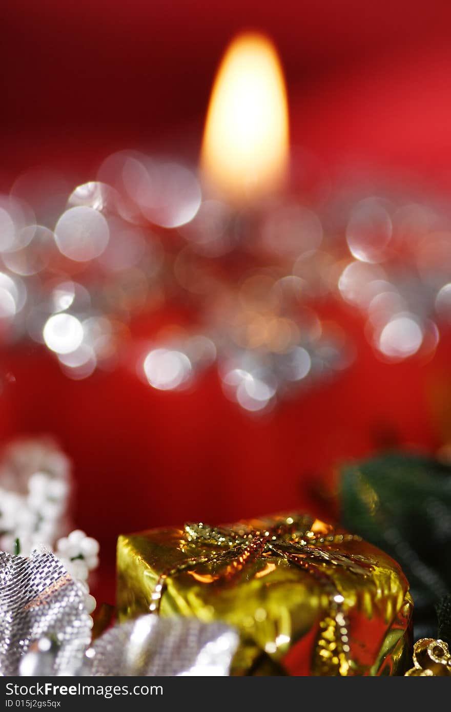 Golden gift box in front of red candle. Narrow depth of field. Golden gift box in front of red candle. Narrow depth of field.