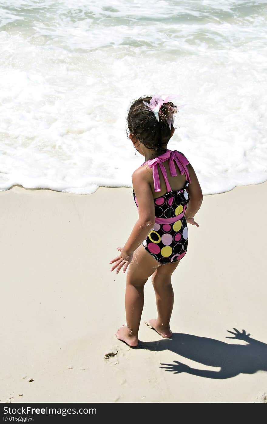 Little girl standing near the ocean bracing herself for the wave that's on the way to get her. Little girl standing near the ocean bracing herself for the wave that's on the way to get her.