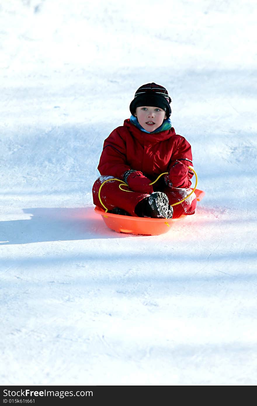 Boy in red in sled going downhill