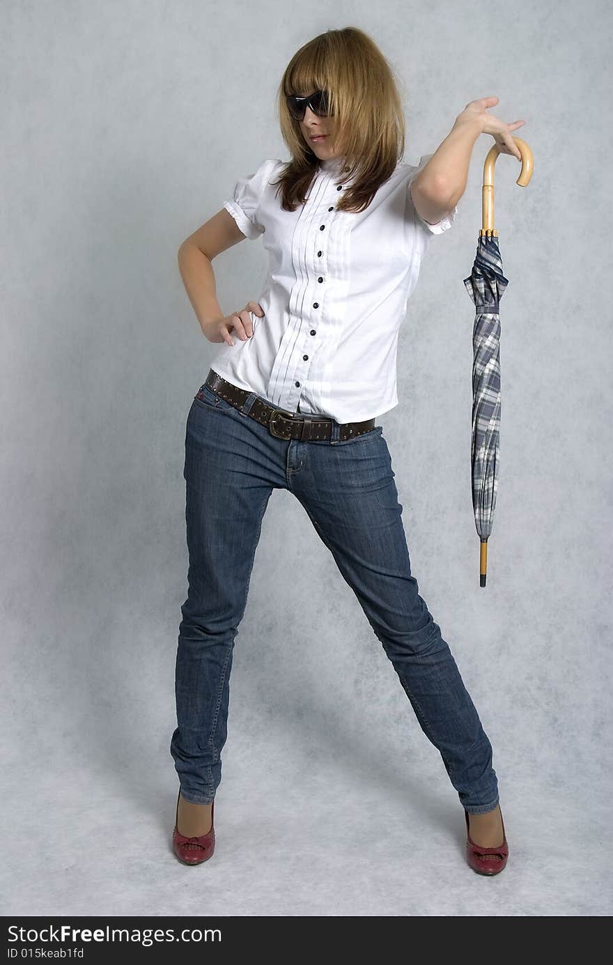 Stylish girl in white blouse and blue jeans with umbrella