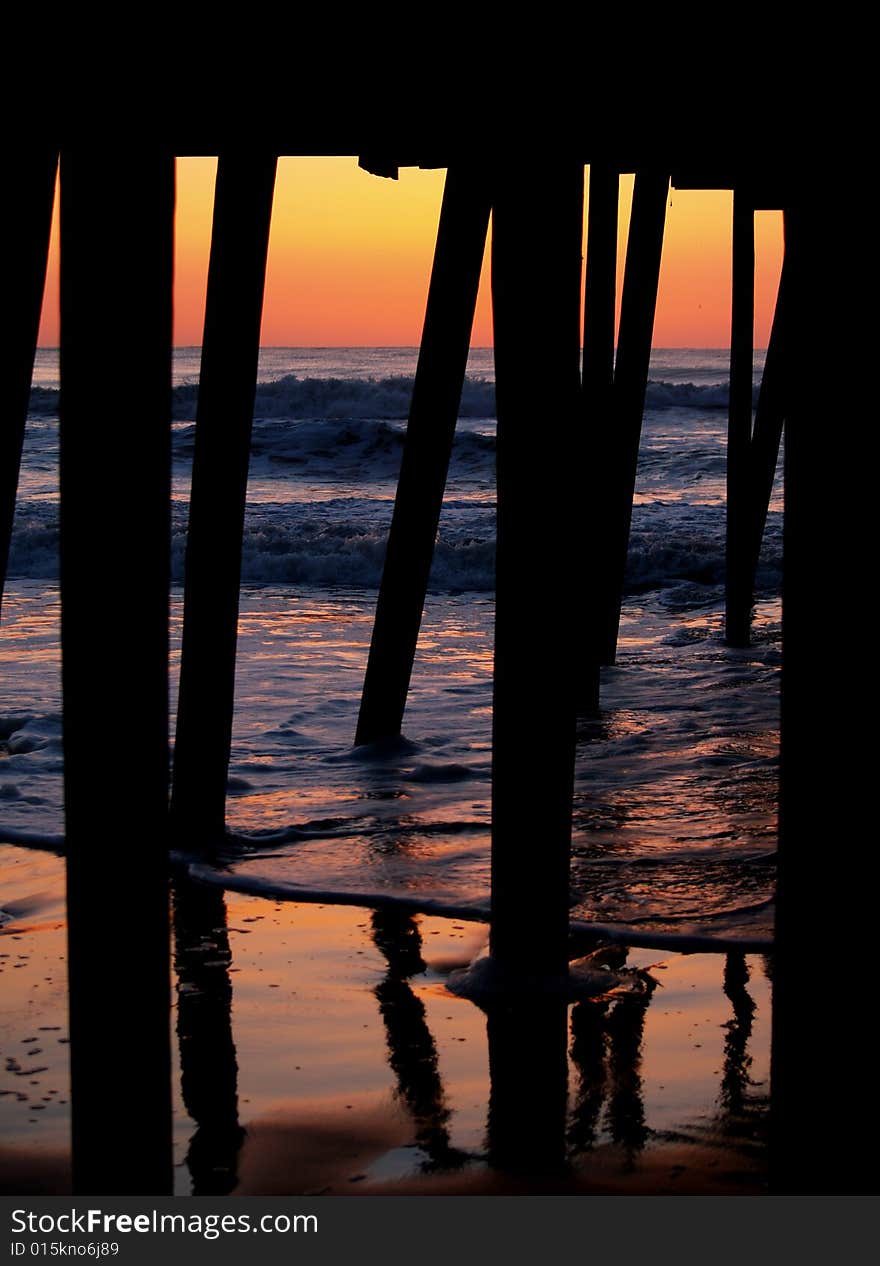 An interesting angle of the sunrise from under a pier as the waves reflect the sunlight. An interesting angle of the sunrise from under a pier as the waves reflect the sunlight.