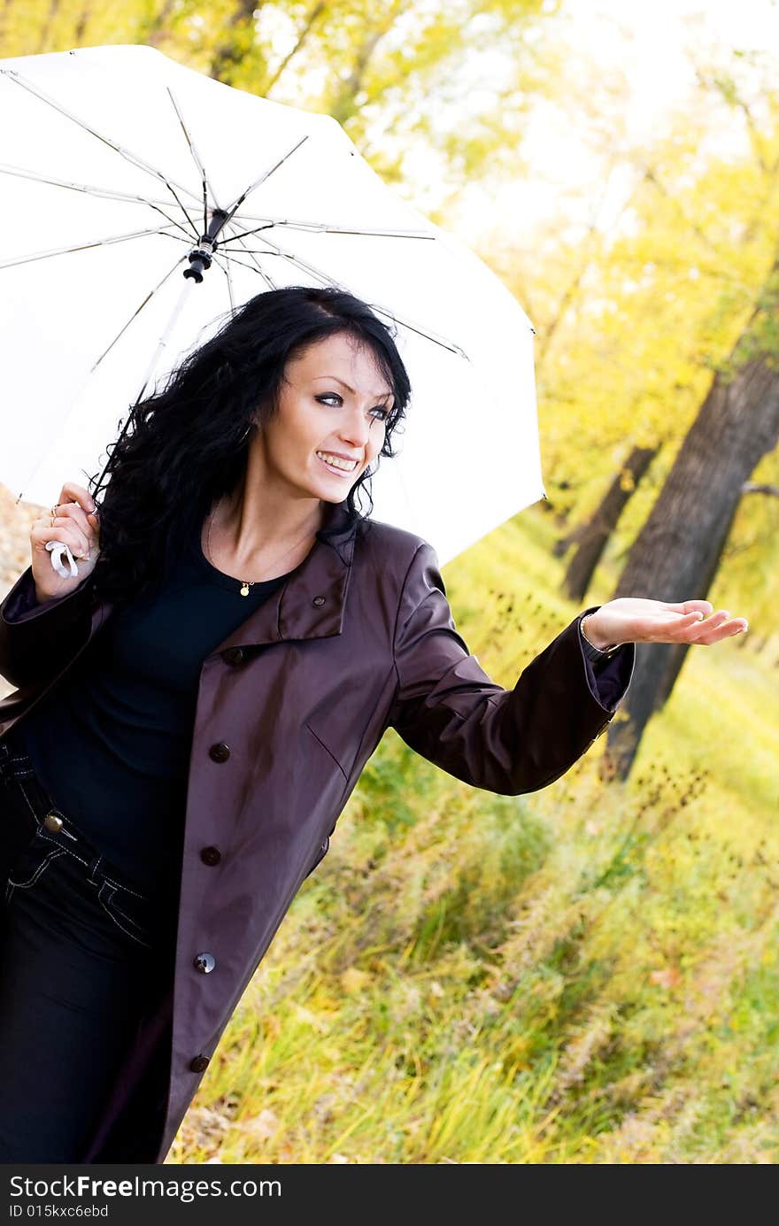 Happy girl with an umbrella in the park checks if it is raining