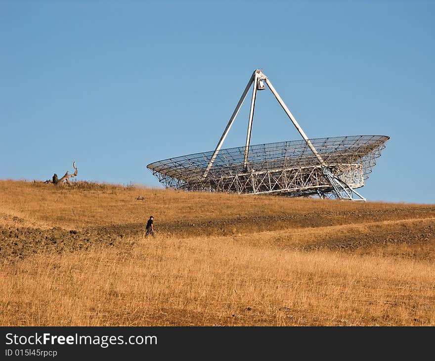 The Stanford satellite dish sits on top of a hill as a man hikes to the top. The Stanford satellite dish sits on top of a hill as a man hikes to the top.