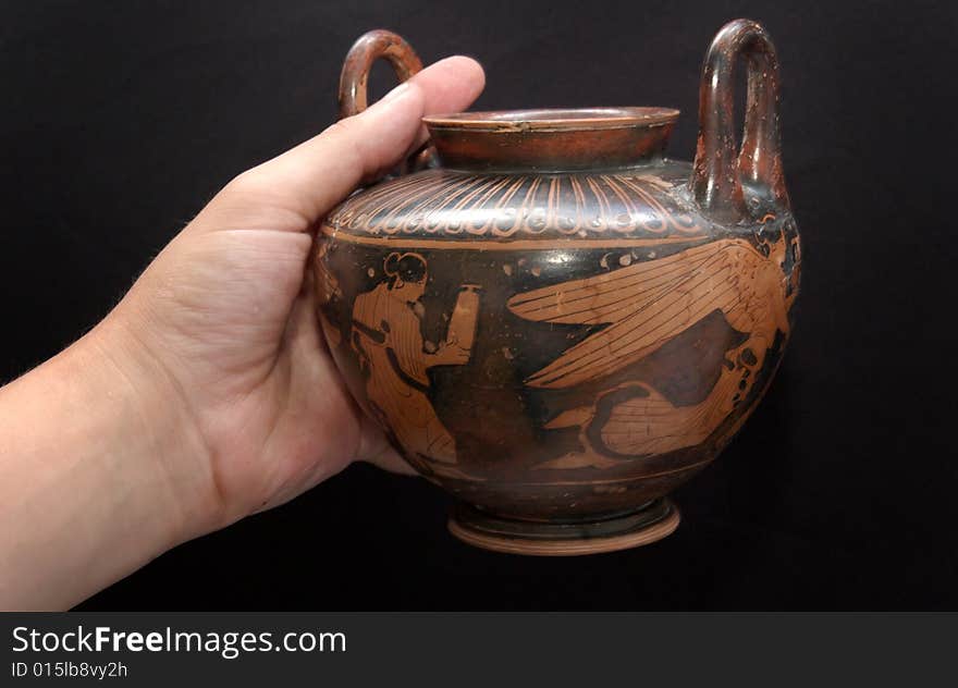 Ancient greek vase in a hand isolated on black