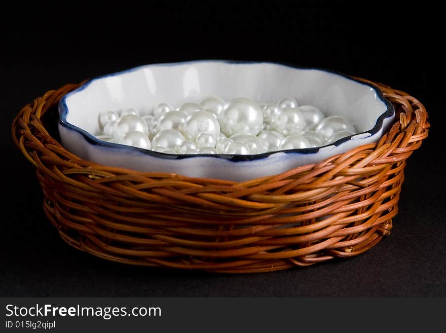 Basket with white pearls isolated on a black background