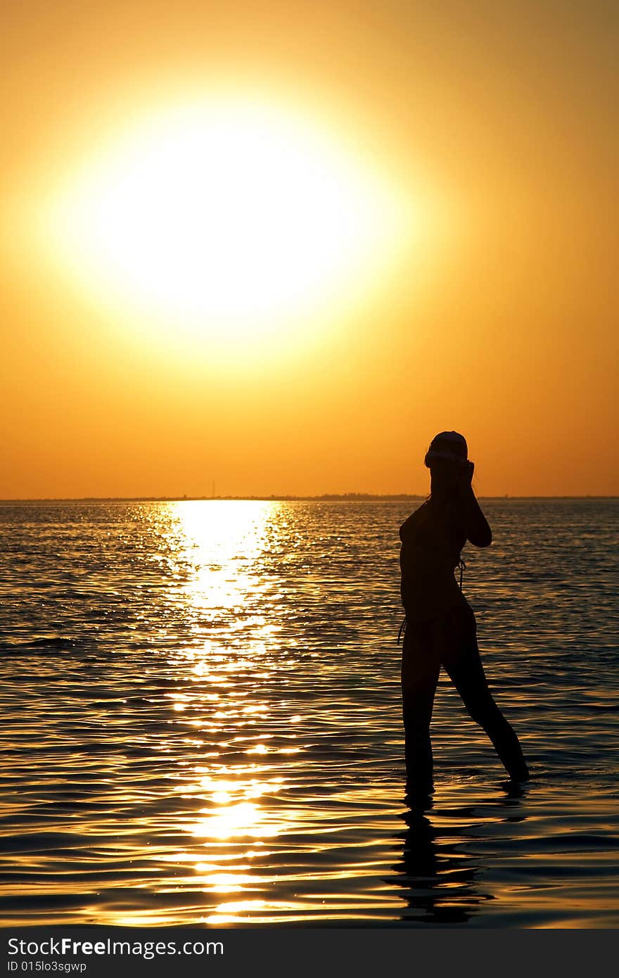 Silhouette of the young woman on a bay on a sunset