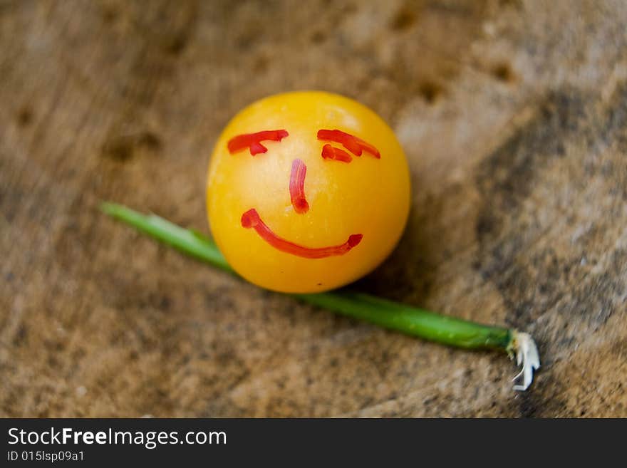 Yellow little plum with face design with stik on wood surface. Yellow little plum with face design with stik on wood surface