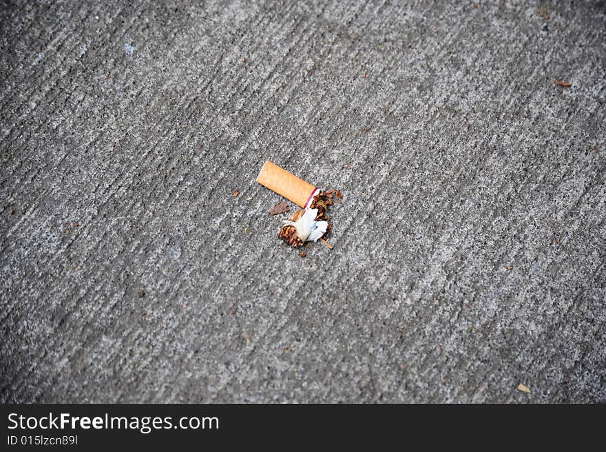 Someone littered the sidewalk with a cigarette butt.