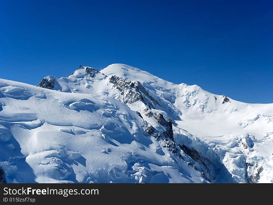 Clear blue sky above snow-covered peak and glacier flown down. Clear blue sky above snow-covered peak and glacier flown down