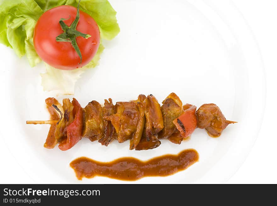 Shashlik on a plate with a tomato and salad leaf