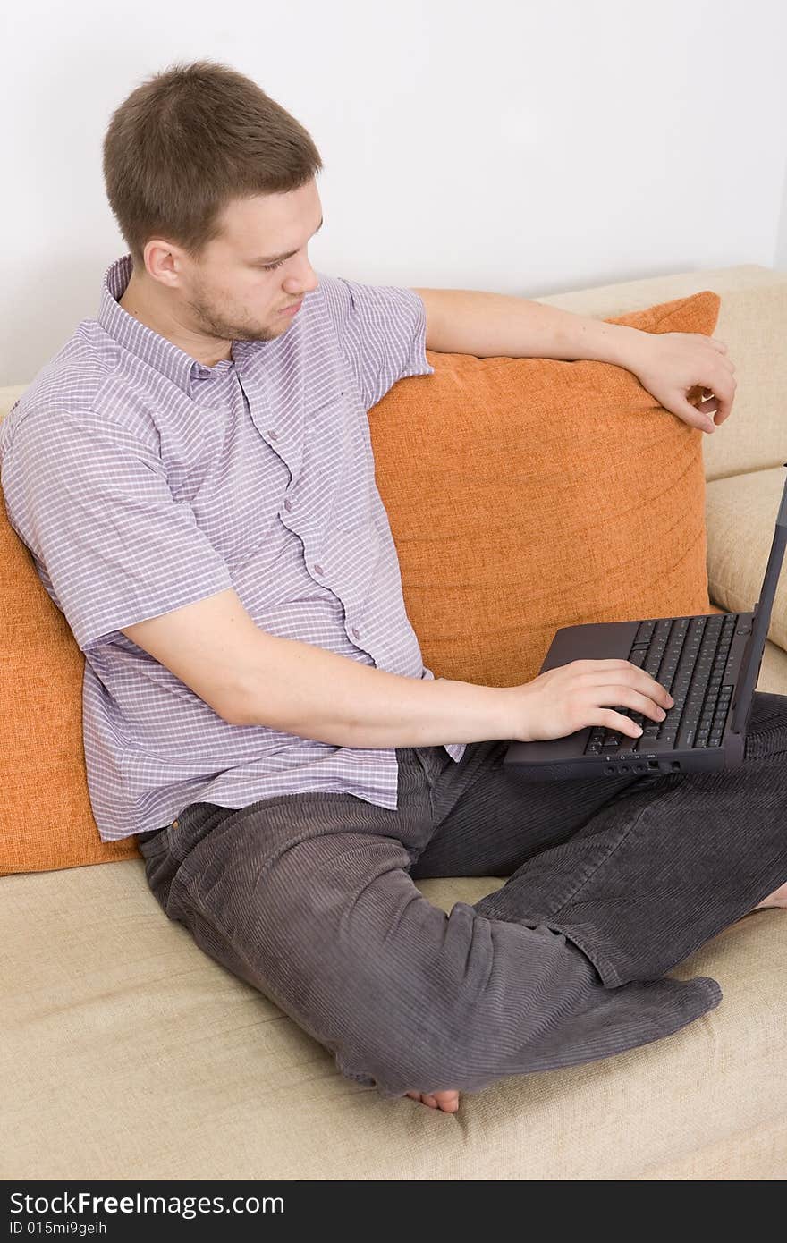 Casual guy sitting on sofa with laptop. Casual guy sitting on sofa with laptop