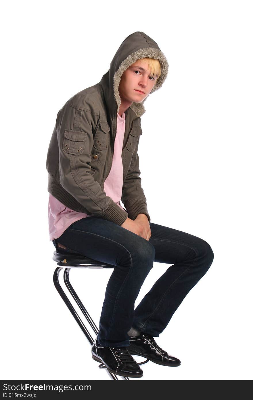 Young man in jacket with fur sits on stool. Isolated