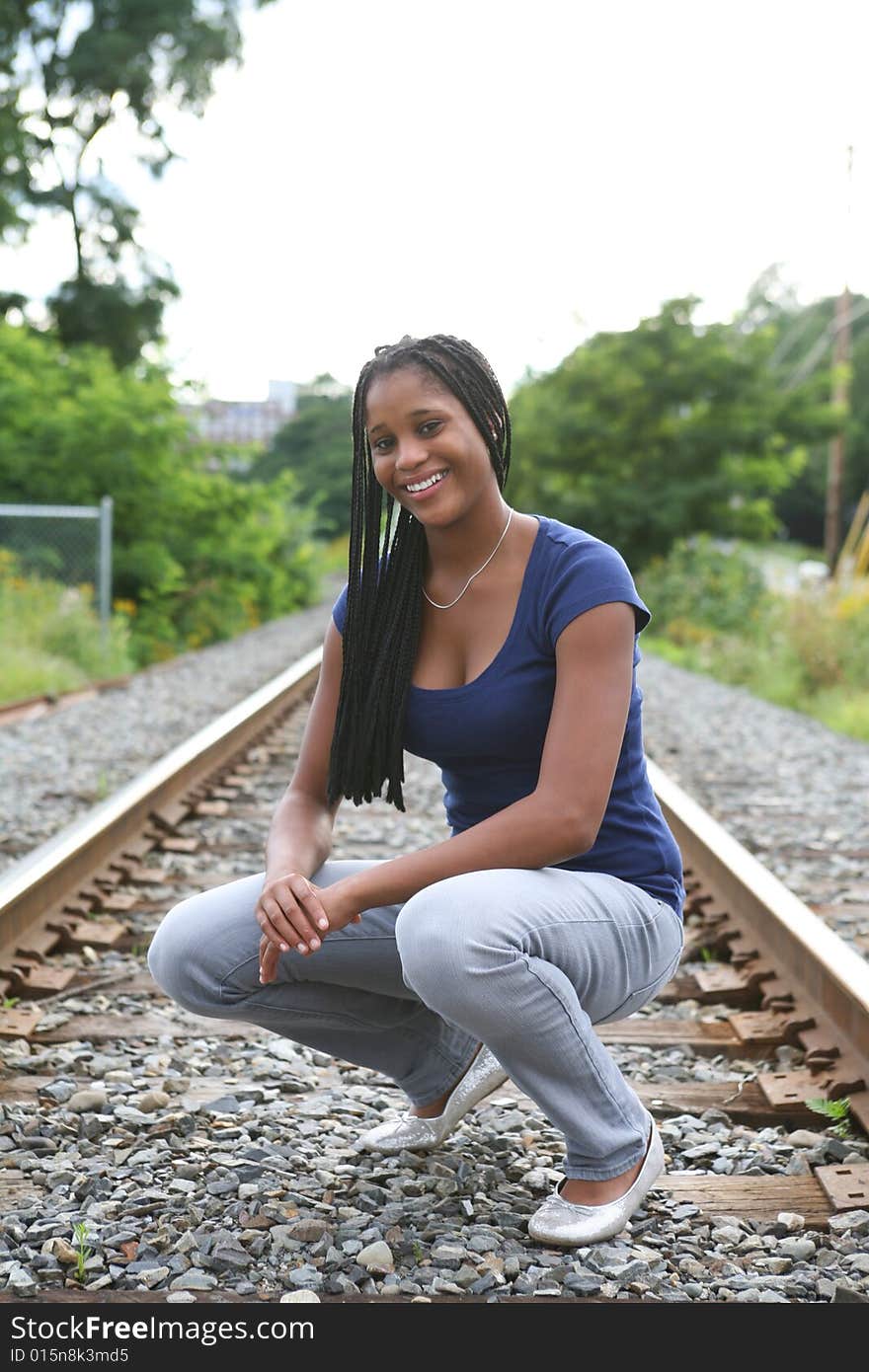 Prety black teenage girl crouching on train tracks. Prety black teenage girl crouching on train tracks