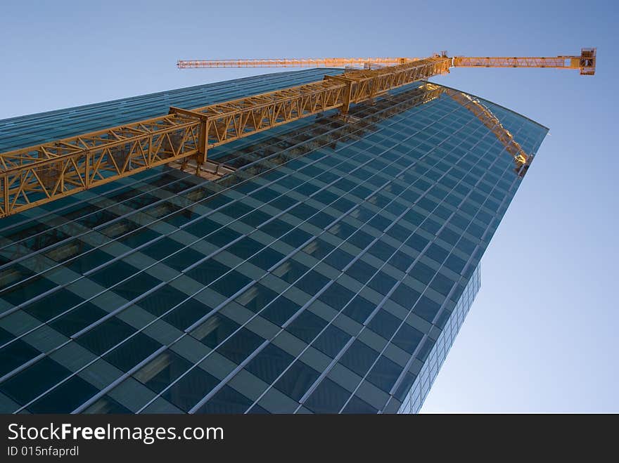 Yellow Crane Reflecting In The Curved Glass Wall