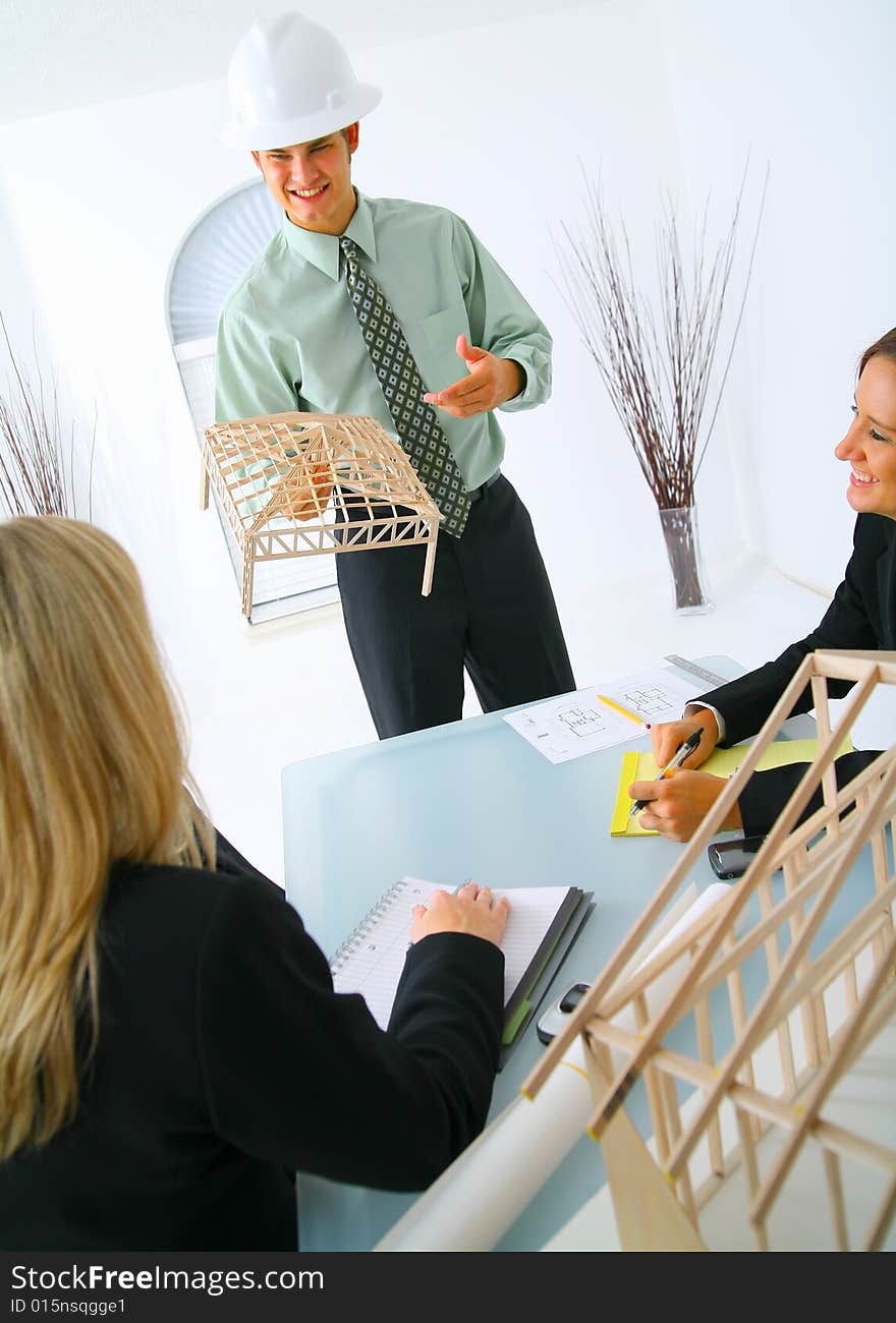 Happy caucasian contractor showing house model to two businesswoman. concept for architecture and construction. Happy caucasian contractor showing house model to two businesswoman. concept for architecture and construction