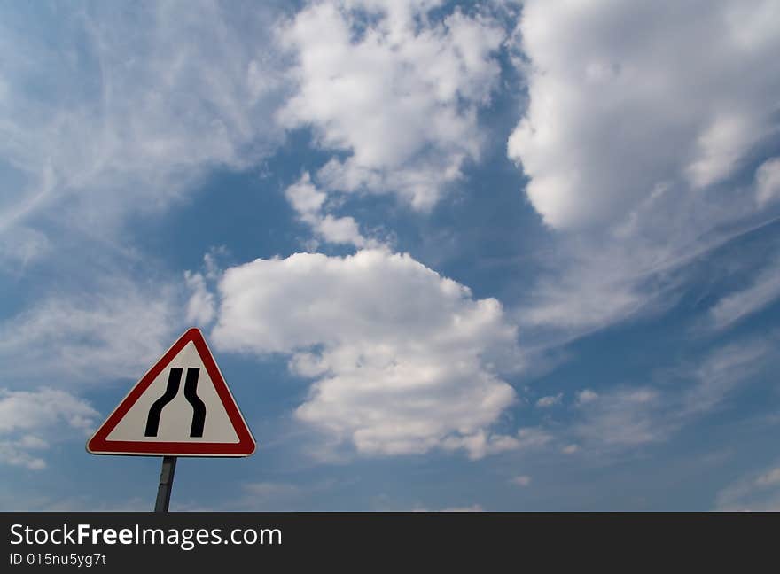 Sign Narrowing a road on background of cloudy sky