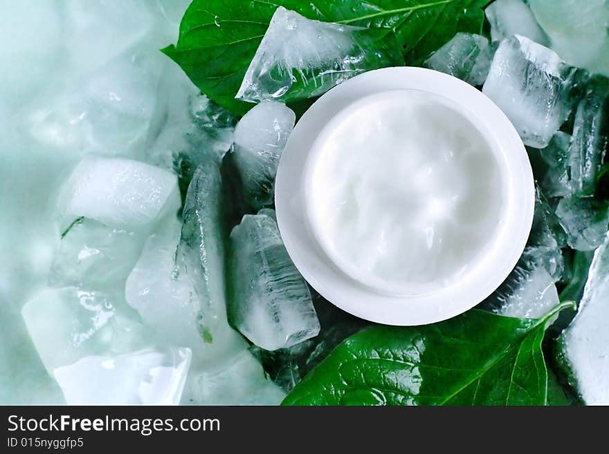 A jar of a cosmetic cream with fresh green leaves and pieces of ice. Beauty concept. A jar of a cosmetic cream with fresh green leaves and pieces of ice. Beauty concept.