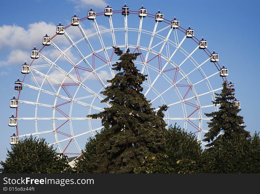 Ferris wheel at trees and blue sky