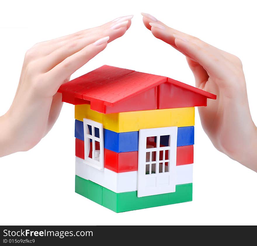 Hands of young woman protect toy colour plastic house with red roof. Hands of young woman protect toy colour plastic house with red roof