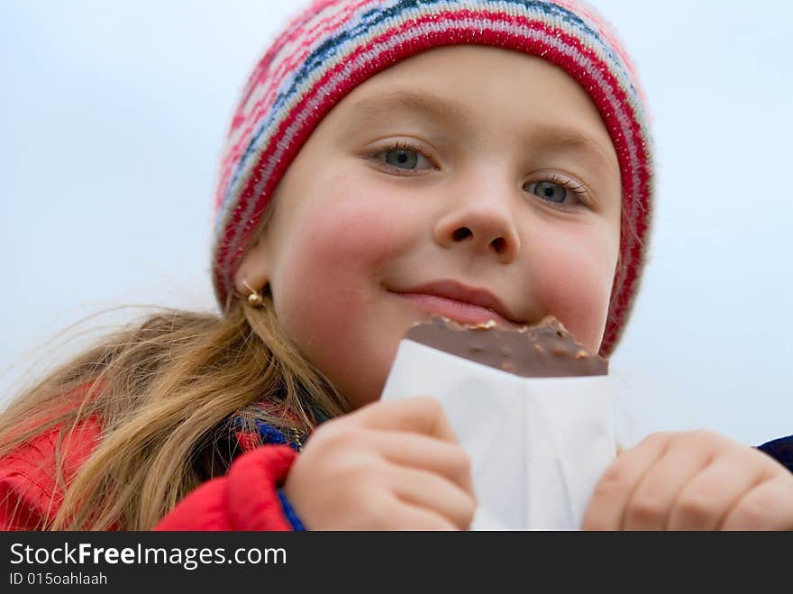 Young girl in a rose cap eats chocolate. Young girl in a rose cap eats chocolate