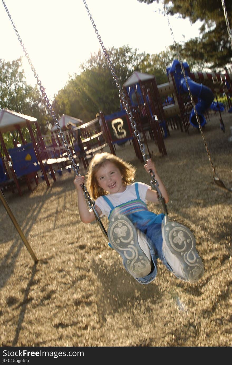 Little girl playing on swing set at a park. Little girl playing on swing set at a park