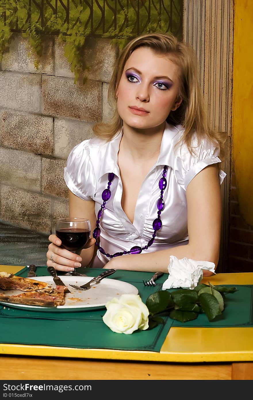 Young woman on dinner in pizzeria with glass of wine in hand.