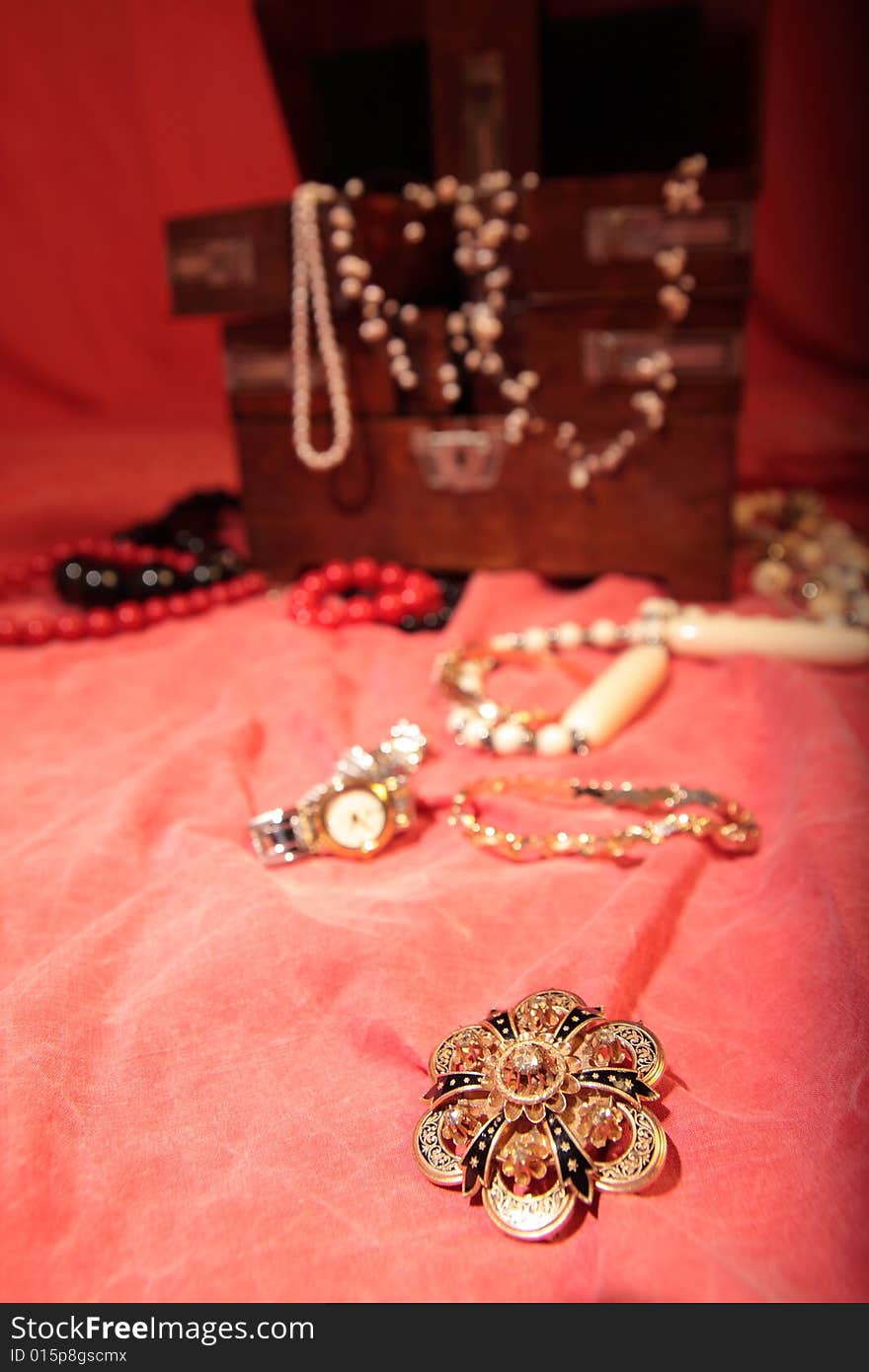 Beautiful golden brooch on red surface and more jewelry in the background