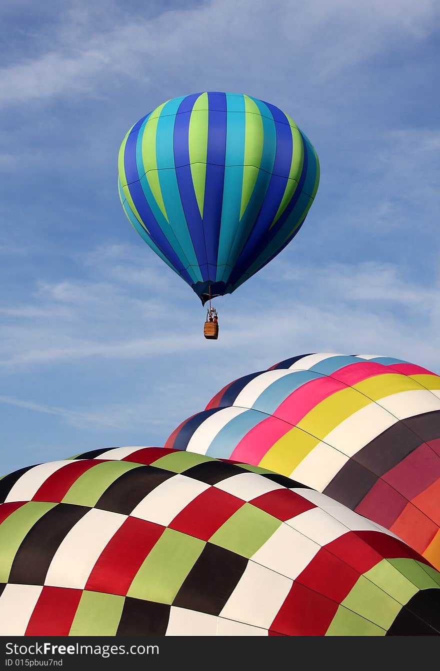 A multi-colored hot air balloon ascending into the clear blue sky