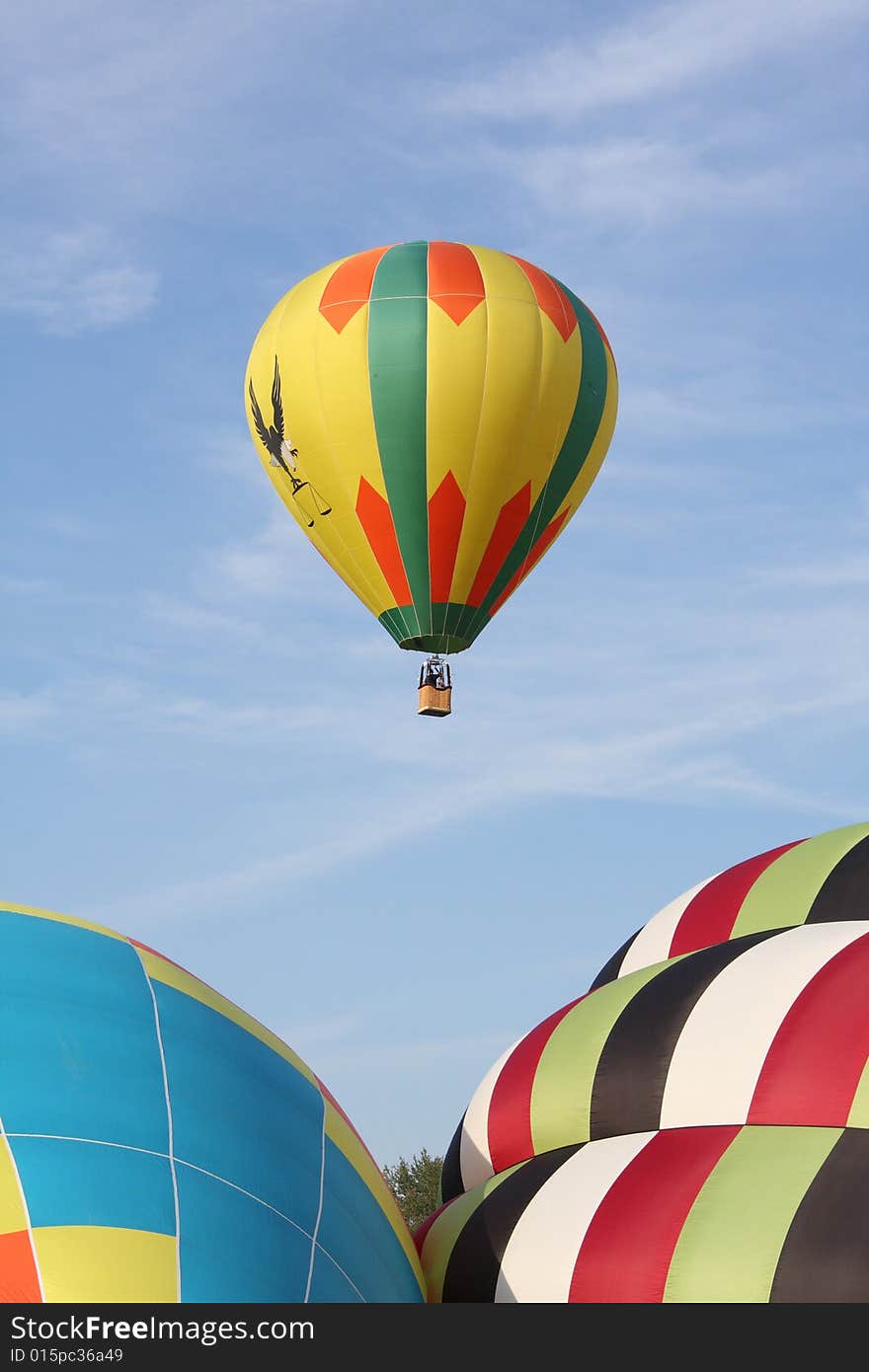 A multi-colored hot air balloon ascending into the clear blue sky