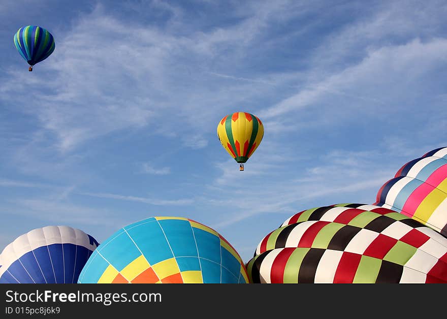 Multi-colored hot air balloons ascending into the clear blue sky