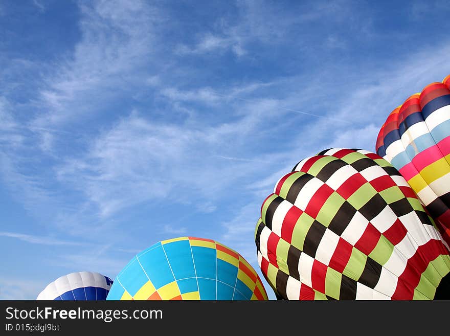 Multi-colored hot air balloons ready to ascend into the clear blue sky