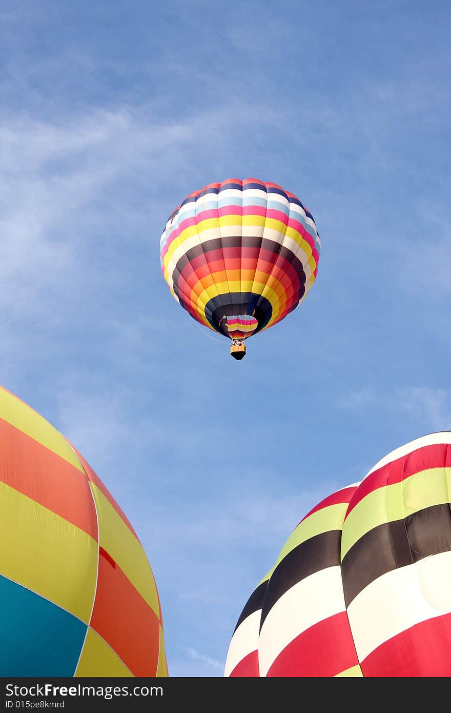 A multi-colored hot air balloon ascending into the clear blue sky