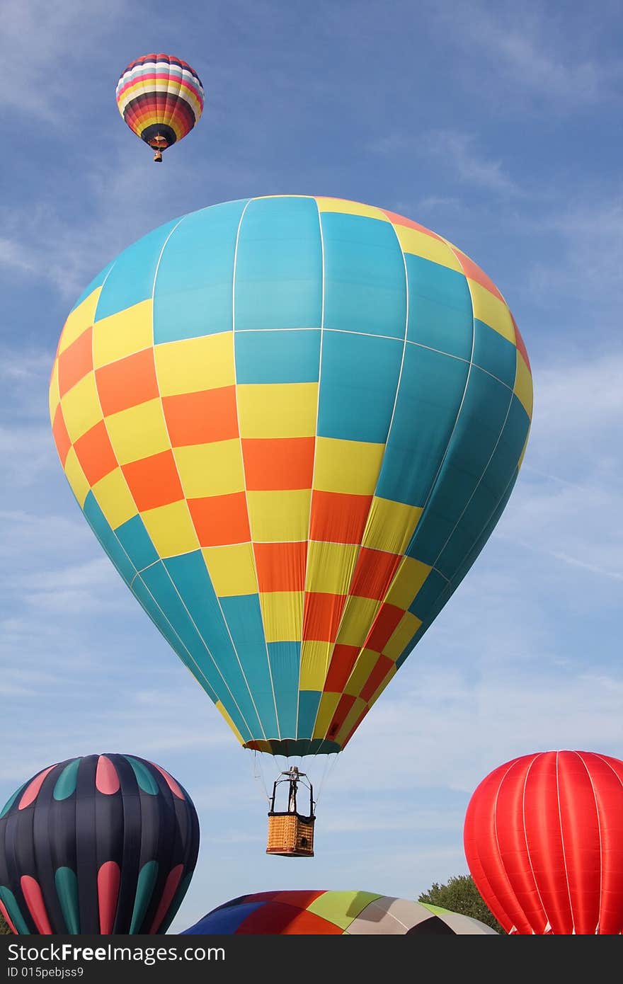 A multi-colored hot air balloon ascending into the clear blue sky