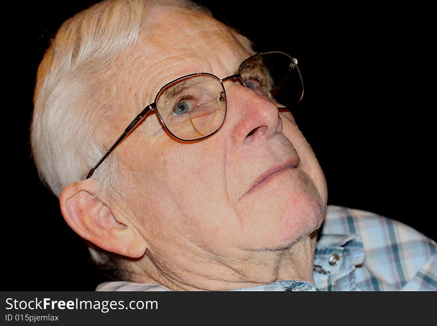 A head shot of a blue-eyed senior wearing glasses with a serious expression.  The background is black. A head shot of a blue-eyed senior wearing glasses with a serious expression.  The background is black.