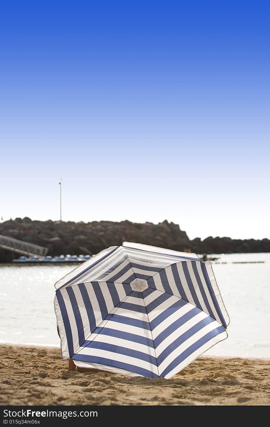 White and blue parasol on desert beach. White and blue parasol on desert beach