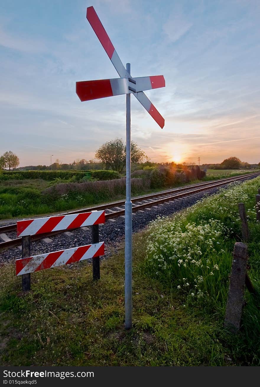 Railway tracks with pastel sunset and traffic sign