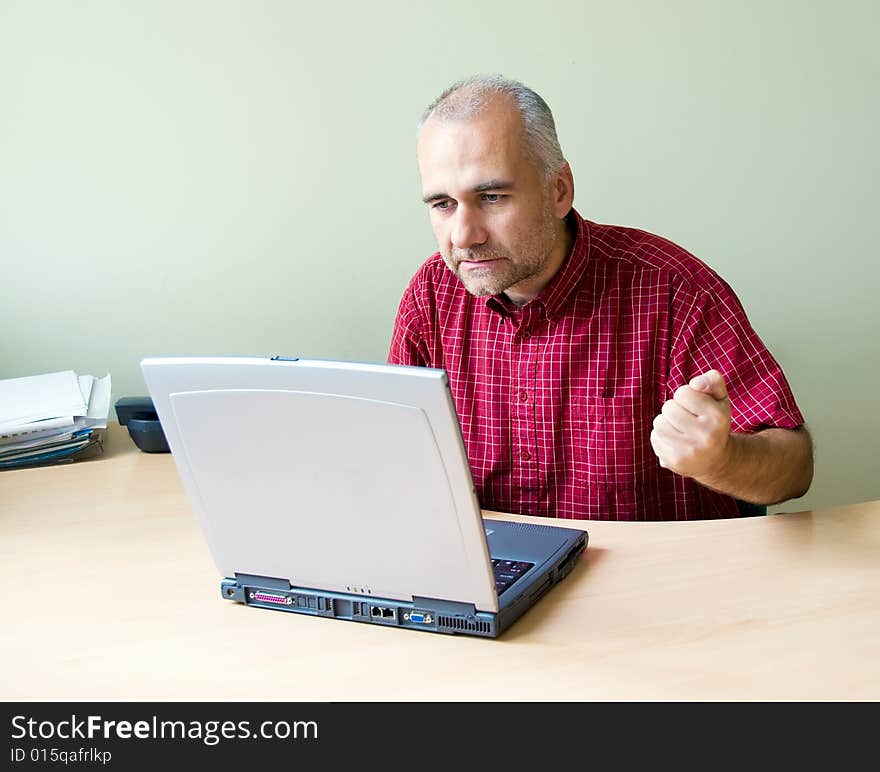 Angry office worker working at the desk with laptop and punching fist on the desk