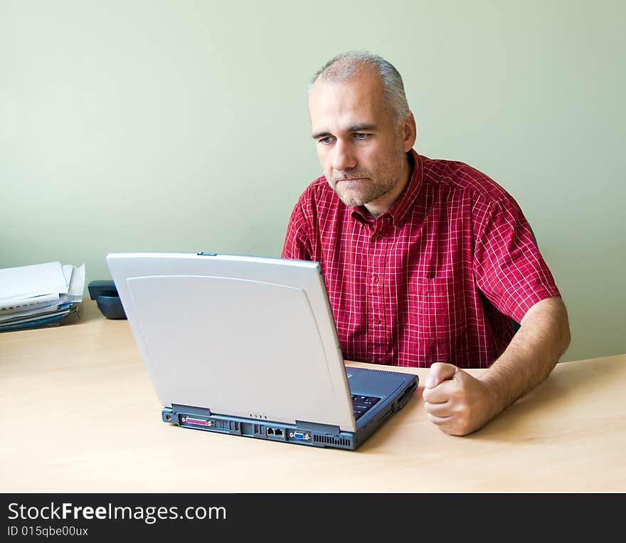 Angry office worker working at the desk with laptop and punching fist on the desk