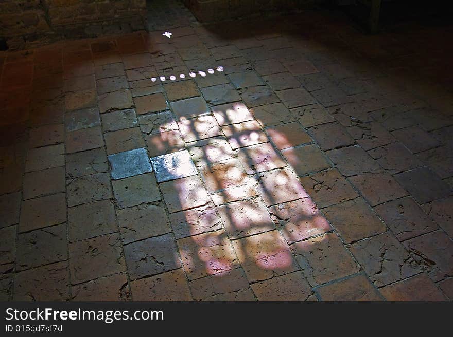 Through a window of the Ruins of Brederode colored light plays with the colored tiles