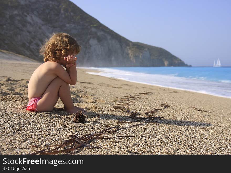 The little girl is looking at the yacht far away across the sea. The little girl is looking at the yacht far away across the sea.