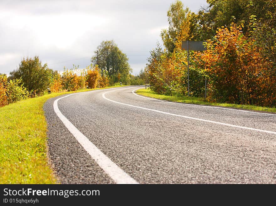 Autumn road. Green and yellow trees. Sun weather