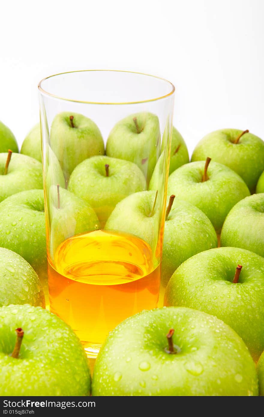 The glass with juice costs among set of green apples. The glass with juice costs among set of green apples