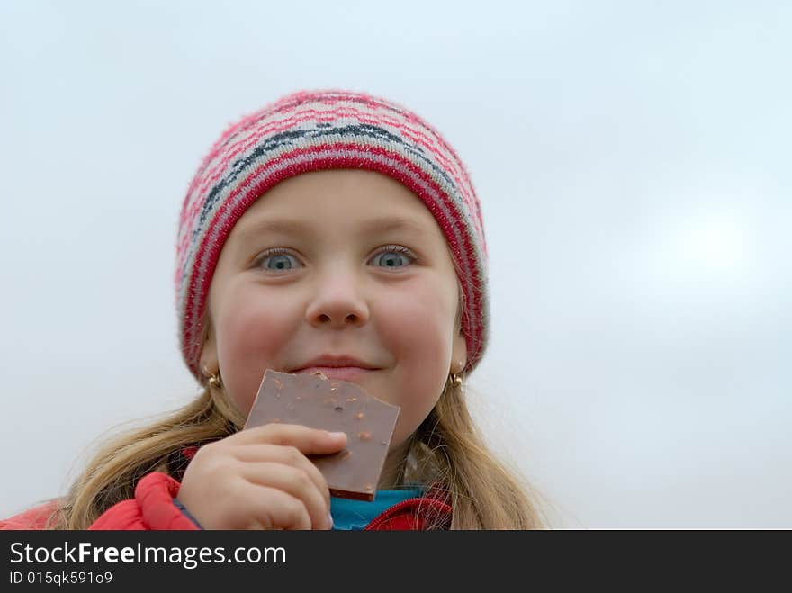 Young girl in a rose cap eats chocolate. Young girl in a rose cap eats chocolate