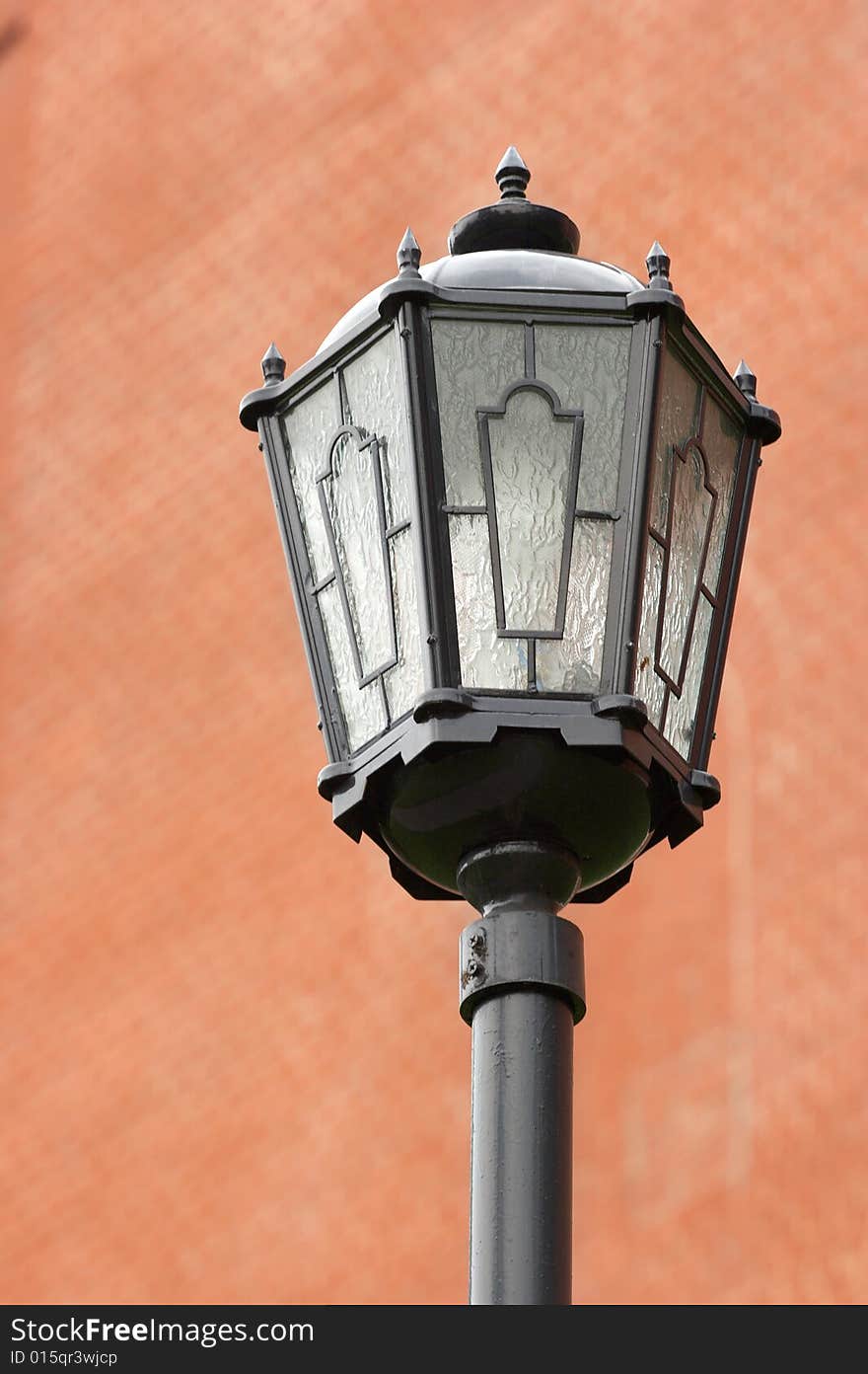 One street lantern against a dim brick wall