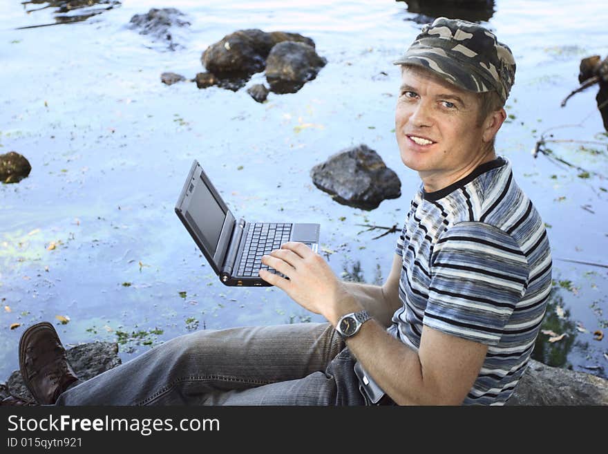 Man works at notebook sitting on stone