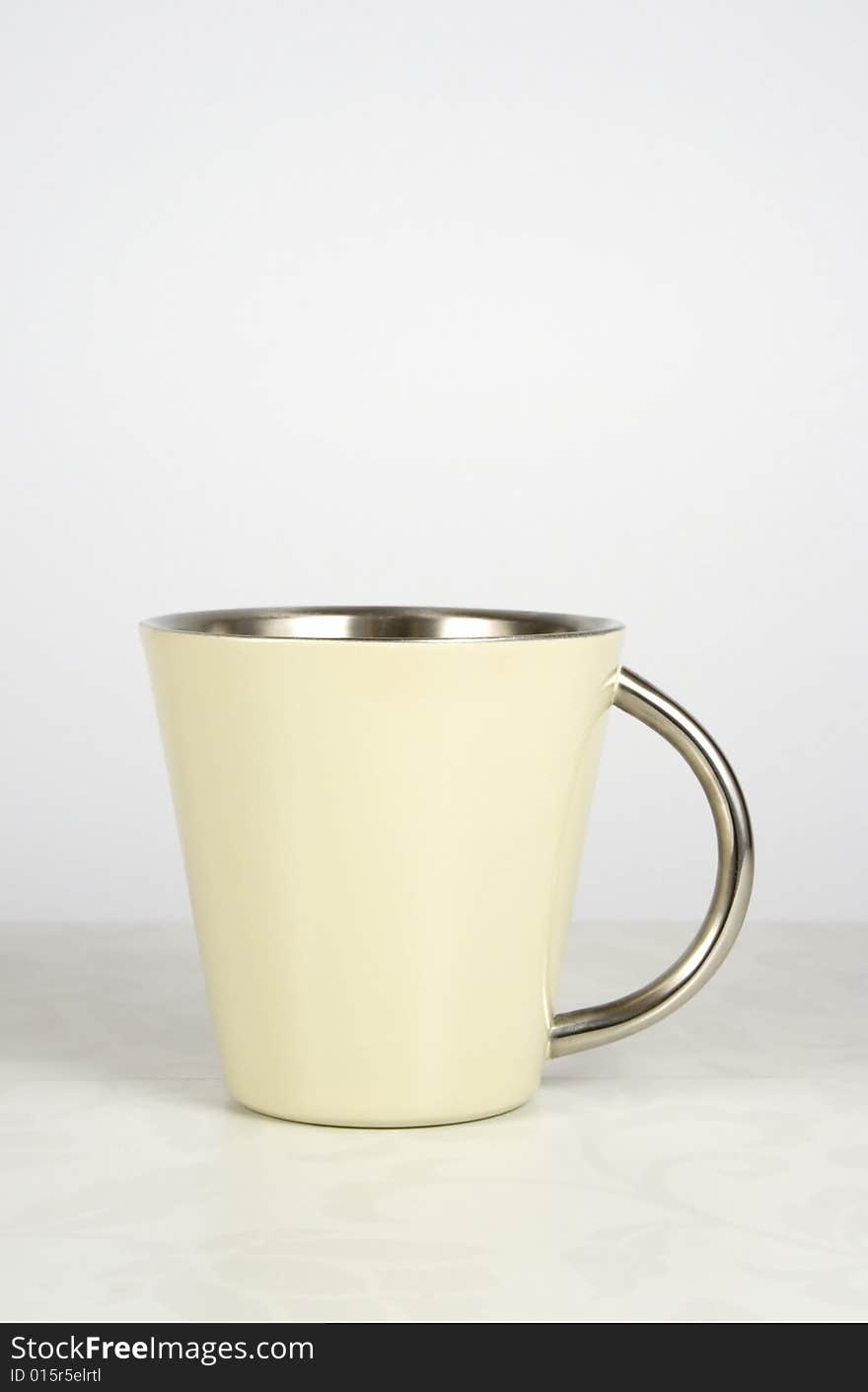 Beige metal mug on flower patterned table