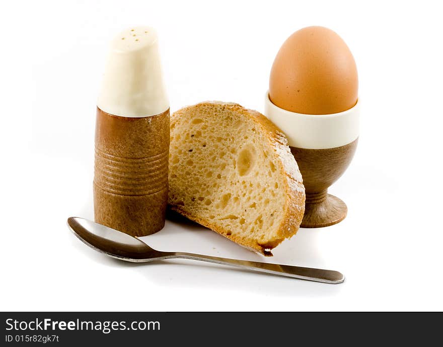 A soft boiled egg, a slice of bread and a saltpot