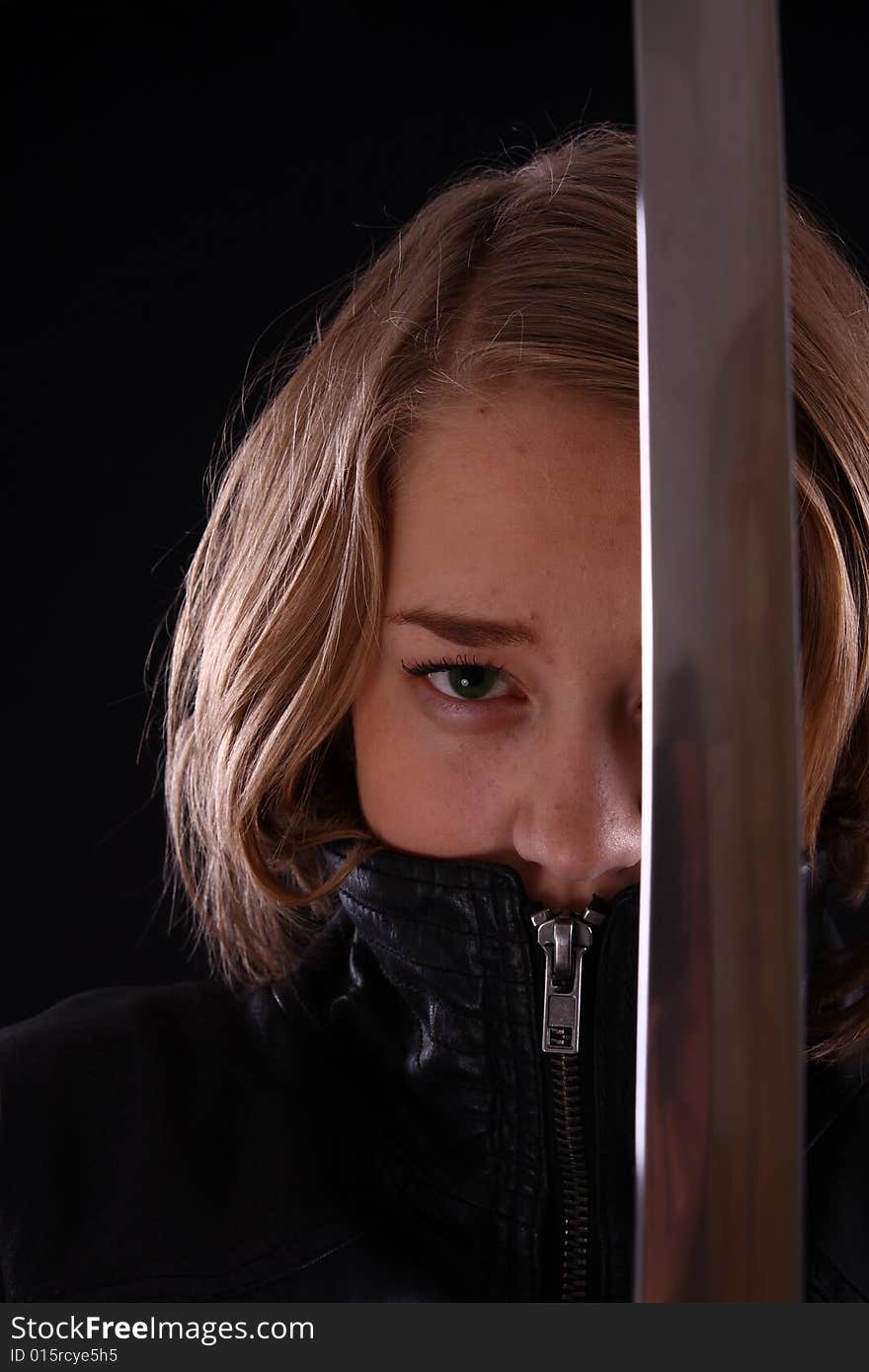 Young woman holding a samurai sword, katana, against black. Young woman holding a samurai sword, katana, against black