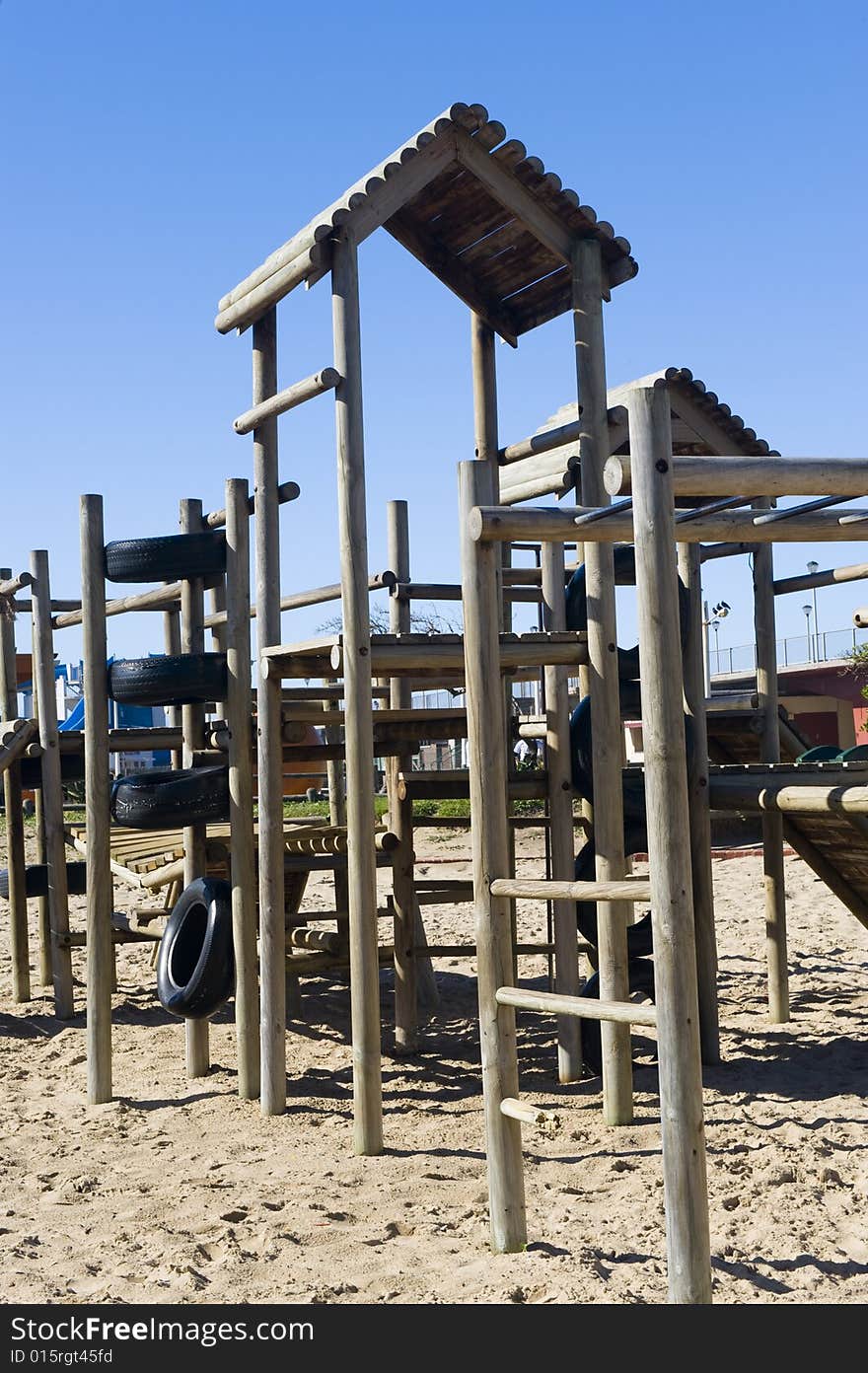 A park next to the beach with a play area for kids containing a wooden jungle-jim. A park next to the beach with a play area for kids containing a wooden jungle-jim.