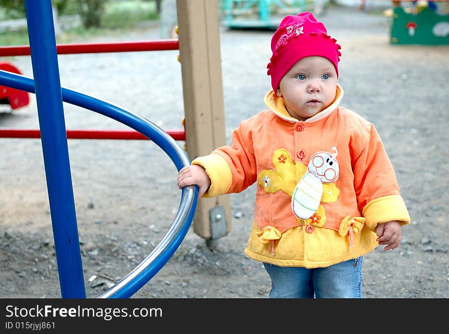 Pretty little girl stay near slide on playground. Pretty little girl stay near slide on playground.